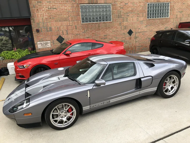 A silver Ford GT and a red Mustang Shelby parked side by side in front of a brick storefront.